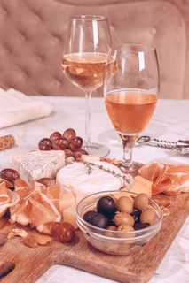 People enjoy a cheese and charcuterie board with various cheeses, meats, fruits, nuts, and olives