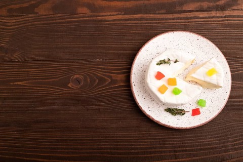 White Camembert mold cheese on brown wooden background, top view, flat lay, copy space