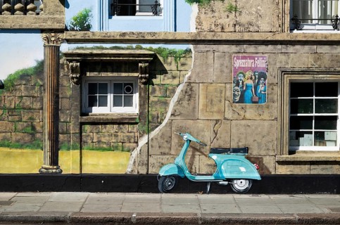 A turquoise painted roller on an illusionistically painted house façade and vintage posters, 143