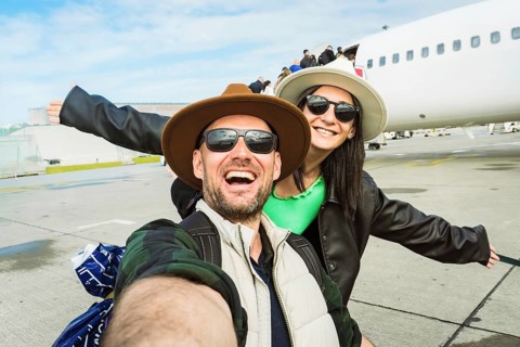Smiling happy man woman passengers taking selfie photo on departure by commercial aircraft