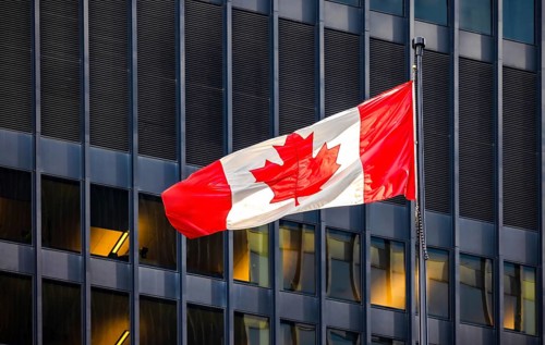 Red and white Canadian flag with a maple leaf waving in the air in downtown Toronto near Ontario