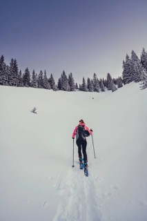 A woman's ski tour at sunrise on the Tegelberg in the Allgäu in the Ammergebirge, Bavaria, Germany
