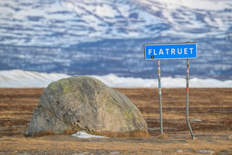 A road sign with the name Flatruet next to a large stone in a snow-covered landscape, Flatruet,