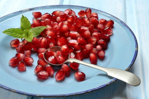 Pomegranate seeds and spoons on plate, Punica granatum