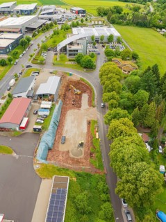 An aerial photo shows a construction site with surrounding buildings and roads in a green