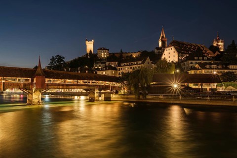 Historic city view at night with illuminated spreuer bridge and reflecting lights in the water,