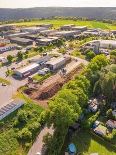 Aerial view of an industrial area with construction site surrounded by green spaces and buildings
