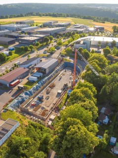 Bird's-eye view of a construction site in an industrial area flanked by nature and a large