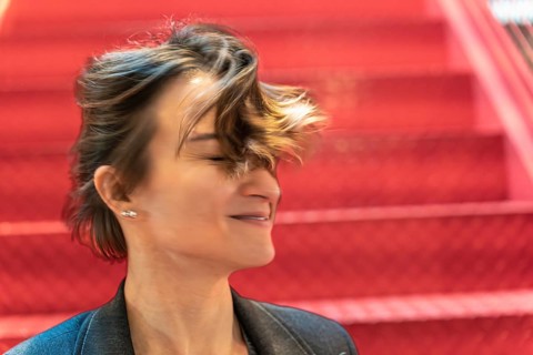 Happy businesswoman laughing with windblown hair against red industrial background
