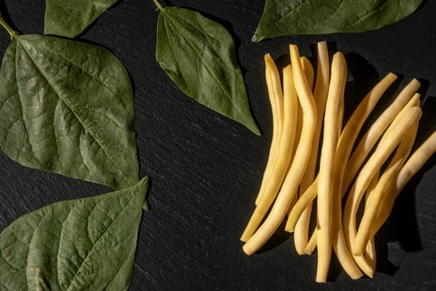 Yellow beans combined with green leaves on a black background