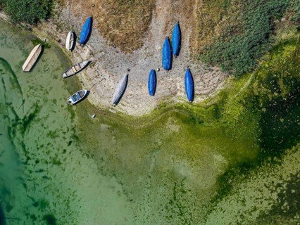 Lake Constance shore on the island of Reichenau with boats and swimmers. The bottom of the lake can