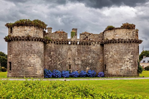 Frontal view of an old stone ruin with round towers against dark clouds, The ruins of the Château