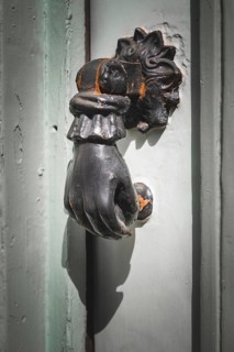 Old French door knocker with hand on a front door in France