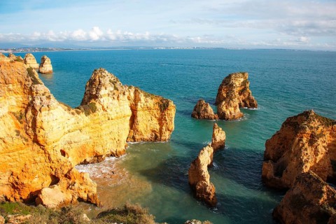 Rocks and cliffs stretch across the azure sea, which adorns an impressive coastal landscape, rocky