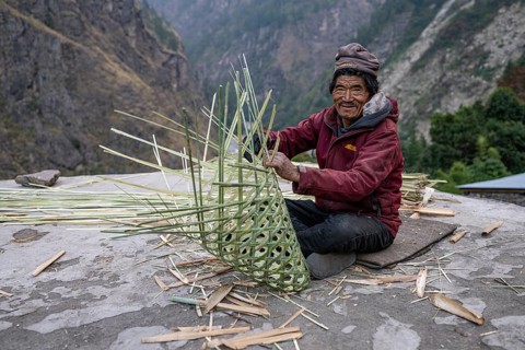Nepalese, local of the Tsumba Tibetan ethnic group weaving a basket, traditional crafts, Tsum