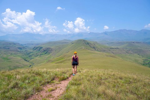 Green hills and valleys, young woman hiking through landscape, Worlds View Hike, Drakensberg, South