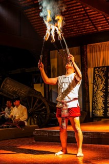 Young Thai man in traditional clothing in a historic show with burning torches, Old Chiang Mai