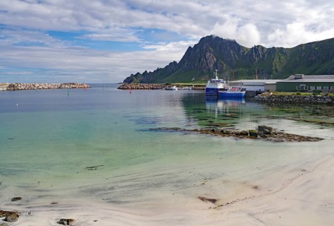 A quiet harbor with boats surrounded by mountains and a partly cloudy sky, Bleik, Bleiksoya,