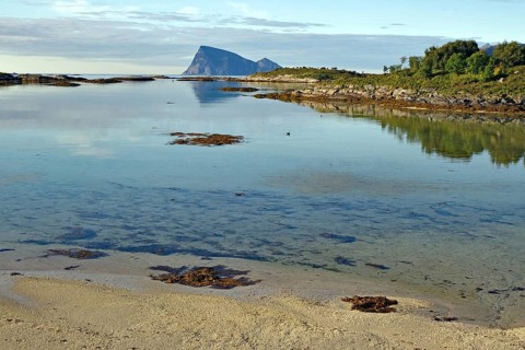 A clear sky reflecting in shallow water with a distant rocky island, Sommaroy, Sommarøy, Troms,