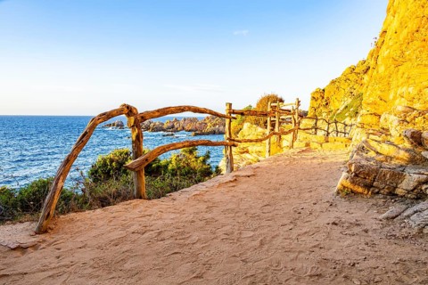 A little trail passing the rocks at the coastline with blue water at Costa Paradiso on a sunny day