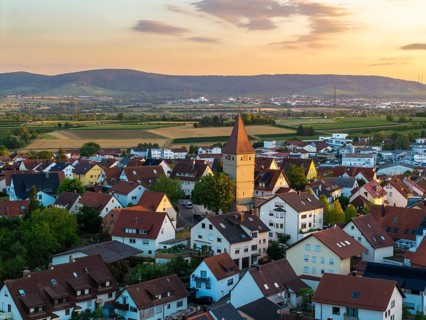 Village in soft evening light with distinctive church tower and red roofs, nestled in hilly
