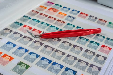 Philately, tweezers on album page with Dutch stamps