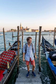 Young man at a boat dock for Venetian gondolas in St. Mark's Square, tourist enjoying the evening,