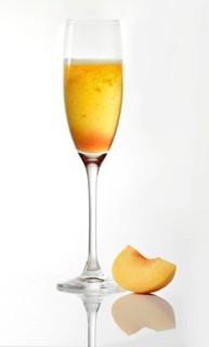 Bellini peach cocktail against a white background, peach wedge as decoration, studio shot