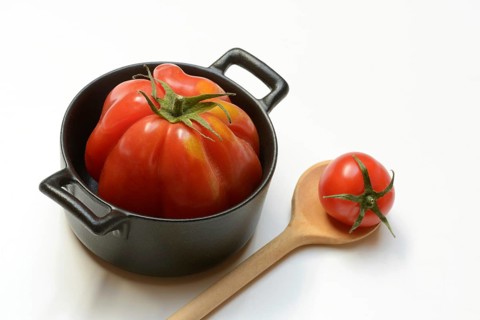 Tomato in pot and cooking spoon, oxheart tomato