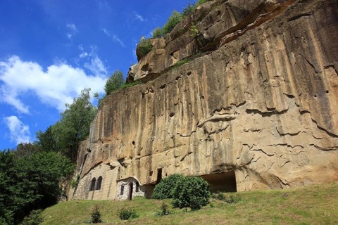 Corbii de Piatra rock monastery, stone ravens carved into a massive, 30-meter high sandstone wall,