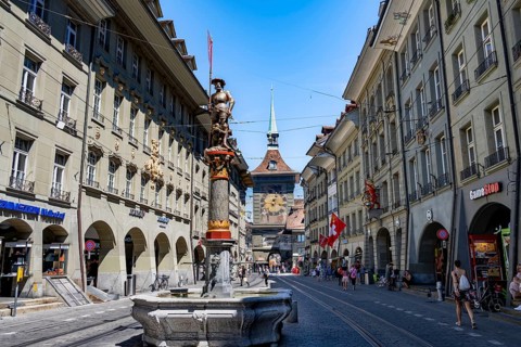 Marktgasse with historic houses and shooting fountains, clock tower Zytglogge behind, old town,