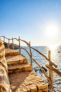 A little trail passing the rocks at the coastline with blue water at Costa Paradiso on a sunny day