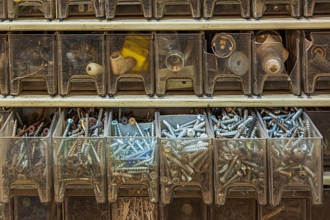 Opened row of plastic parts drawers in cabinet showing mixed phillips, robertson and flathead