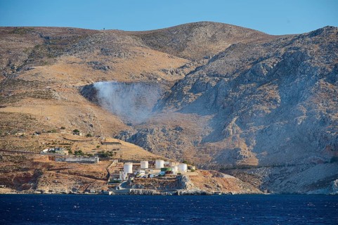Waste incineration plant, tanks, dry mountain landscape with industrial plant and blue sea in the