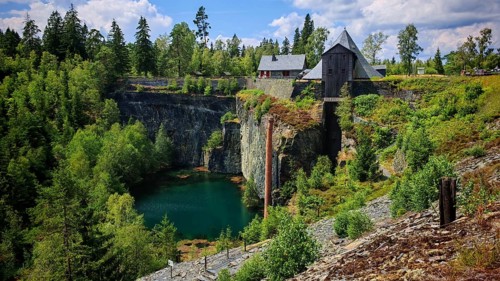 A picturesque quarry lake, slate quarry surrounded by tall rocks and trees, houses in the