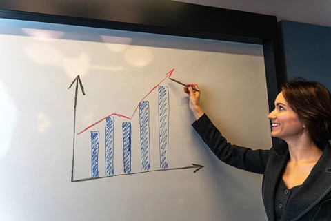 Confident businesswoman smiling at positive growth chart during corporate presentation