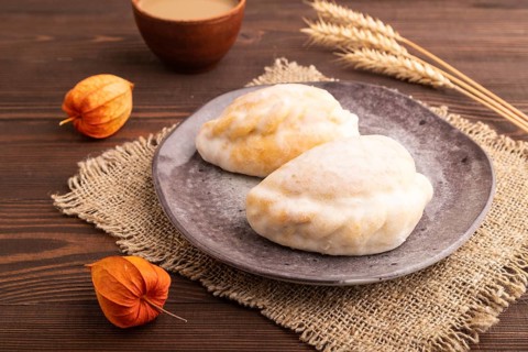 Glazed Pies with Cowberry jam on brown wooden background and linen textile, cup of coffee, side