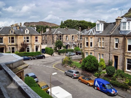 View from a window of traditional Scottish stone-look townhouses, historic residential street