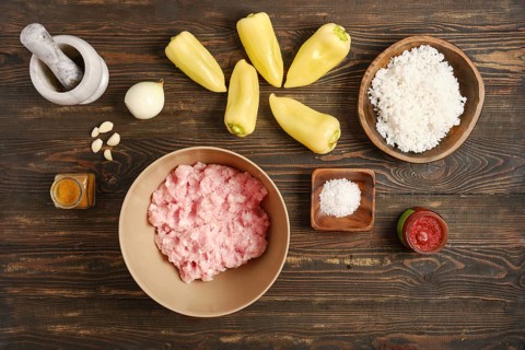 Raw and fresh ingredients for cooking bell peppers stuffed with minced meat on rustic wooden table