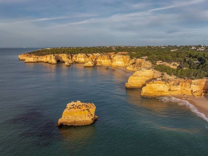 Drone view of Praia da Marinha beach in Algarve, Portugal, with golden cliffs, an offshore rock,