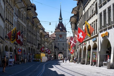 Market alleyway with historic houses decorated with cantonal flags and Swiss national flags, cage