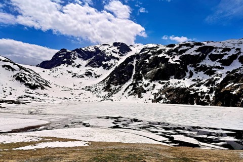 Ice floes drift in the half-frozen upper Murgsee, in the foreground, white flowering spring