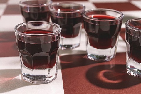 There are small glasses with a red drink on the table. chocolate liqueur, Soft light creates