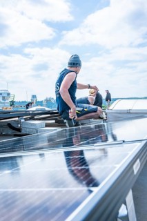 Workers install solar cells on a roof under a blue sky, PV Assembly, Perrot company, Calw, Germany