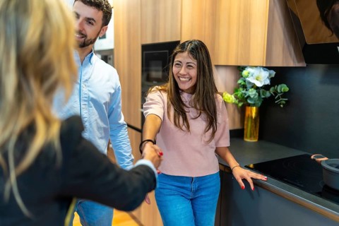 Young couple meeting with a sales representative, shaking hands in a modern kitchen showroom,