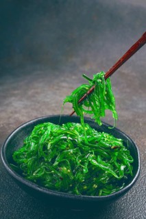 Chuka salad, made from fresh seaweed, with sesame dressing, served in a black bowl, with chopsticks