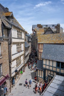 Tourists flock through a medieval alley surrounded by traditional half-timbered houses within the