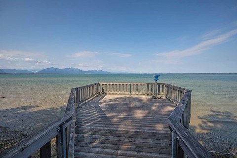 Daytime horizontal view along a wooden observation platform with a blue coin-operated telescope
