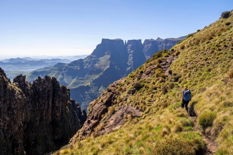 Young hiker looking at the impressive mountains and cliffs of the Drakensberg Mountains, hiking