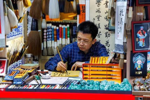 Calligrapher writes Chinese characters at art stall, Old Town Bazaar, Shanghai, China